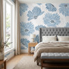 Blue watercolor floral wallpaper in a bedroom with upholstered bed, window light, and calm Scandinavian-inspired decor