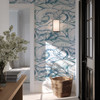 Marina blue Atlantic wave wallpaper in 52 inch repeat styled in a coastal entryway with black door, wall sconce, woven basket, and natural light