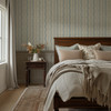 Elsie Heritage Blue floral stripe wallpaper in 13 inch repeat styled in a cozy bedroom with cream bedding, wood nightstand, and English country decor