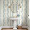 Elsie Heritage Blue floral stripe wallpaper in 52 inch repeat styled in a classic bathroom with pedestal sink, oval mirror, brass sconces, and blue botanical stripe walls