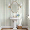 Elsie Heritage Blue floral stripe wallpaper in 13 inch repeat styled in a classic bathroom with pedestal sink, oval mirror, brass sconces, and blue botanical stripe walls