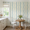 Elsie Heritage Blue floral stripe wallpaper in 52 inch repeat styled in a bright kitchen dining nook with round wood table, white chairs, flowers, and cottage stripe walls