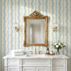 Elsie Heritage Blue floral stripe wallpaper in 26 inch repeat styled in a cottage bathroom with gold mirror, brass sconces, white vanity, and vintage blue botanical stripes