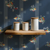 Fruit Compote Navy Blue retro fruit wallpaper in 26 inch repeat shown with white kitchen jars on a wood shelf and vintage kitchen wall decor