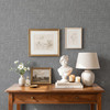 Grey linen look wallpaper in a cozy bedroom with warm wood furniture and neutral bedding