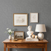 Grey linen look wallpaper in a cozy bedroom with warm wood furniture and neutral bedding