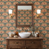 Terracotta and green botanical wallpaper in a bathroom with dark wood vanity, square mirror, and vintage sconces