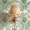 Sigrid Sage Nordic Botanical Wallpaper in 26 inch repeat shown close up with brass wall sconce and sage green botanical floral pattern