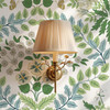 Sigrid Sage Nordic Botanical Wallpaper in 52 inch repeat shown close up with brass wall sconce and larger sage green botanical pattern