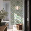 Sigrid Sage Nordic Botanical Wallpaper in 26 inch repeat styled in an entryway with basket, wall light, doorway, and fresh green botanical wallpaper