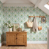 Sigrid Sage Nordic Botanical Wallpaper in 26 inch repeat styled in an attic mudroom with wood cabinet, coat hooks, woven bags, and green botanical wall decor