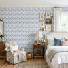 Angelique Blue Floral Wallpaper in 13 inch repeat styled in a grandmillennial bedroom with white bedding, side chair, framed art, and blue botanical wallpaper