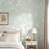 Celia Mint Botanical Wallpaper styled in a bright bedroom with white bedding, nightstand, table lamp, soft curtains, and airy mint botanical walls
