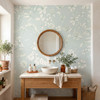 Celia Mint Botanical Wallpaper styled in a spa bathroom with wood vanity, round mirror, white vessel sink, plants, and soft mint botanical wall decor