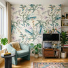 Eden Watercolor Floral Wallpaper styled in a bohemian living room with teal chair, plants, media cabinet, colorful rug, and large watercolor floral wall decor