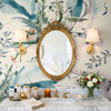 Eden Watercolor Floral Wallpaper styled in a maximalist bathroom with gold oval mirror, brass sconces, marble vanity, flowers, and soft watercolor botanical walls