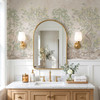 Antique beige chinoiserie wallpaper with flowering trees and birds in a refined bathroom with brass sconces and wood vanity
