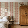 Elsie Sunbaked Clay floral stripe wallpaper beside a wood armoire in a farmhouse bedroom, 26 inch repeat