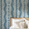 Blue flowers and winding stripes of Elsie Delft Revival wallpaper above a woven headboard, 52 inch repeat