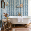 Large-scale Elsie Delft Revival blue floral stripes behind a freestanding bathtub, 52 inch repeat