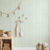 Elsie Ivory Mint Wallpaper in Serene Nursery With Natural Wood Dresser and Soft Green Stripes