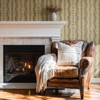 Medium-scale Elsie Walnut and Butter striped wallpaper beside a white fireplace and vintage brown leather reading chair