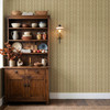 Small-scale brown and butter floral stripe wallpaper behind an antique dining cabinet with pottery and brass lighting