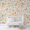 Madison nursery wallpaper with pink and golden yellow flowers and green foliage behind a white spindle crib beside a pale wooden rocking horse.