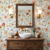 Madison wildflower wallpaper with prominent pink and yellow blooms around a rectangular wood-framed mirror, twin wall sconces and a white vessel sink.