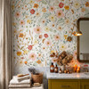 Madison pink and yellow floral wallpaper above a mustard bathroom vanity with a pale countertop, amber bottles, flowers and folded towels.