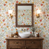 Madison floral wallpaper in a finer pink, yellow and sage pattern behind a wooden bathroom vanity, white vessel sink and rectangular mirror.