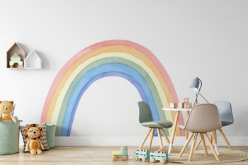 Pastel watercolor rainbow nursery wall decal displayed above a natural wood bench with children’s toys
