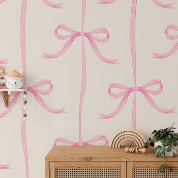 Large-scale pink ribbon bow wallpaper above a natural wood nursery cabinet with rainbow décor
