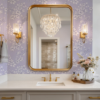 Elegant bathroom featuring Eleanor Lavender Roses English cottage floral wallpaper with gold mirror and brass fixtures.