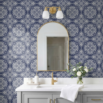 Navy blue geometric tile wallpaper in 26-inch repeat in a modern French bathroom with arched mirror and brass sconces