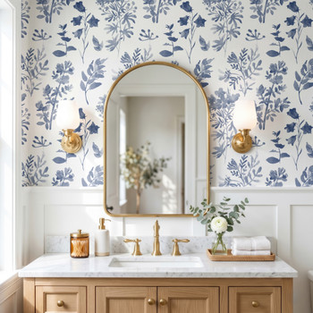 Angelique Blue Floral Wallpaper in 26 inch repeat styled in a bathroom vanity with oval mirror, brass sconces, wood cabinet, and large blue botanical wall pattern