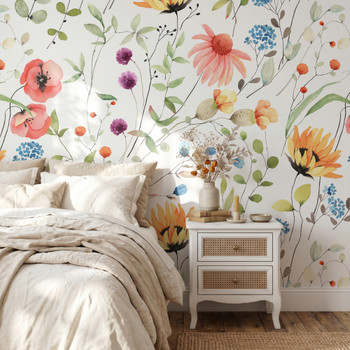 Eloise Wildflower Wallpaper styled in a bright bedroom with white bedding, wood nightstand, colorful watercolor flowers, and cheerful cottage wall decor