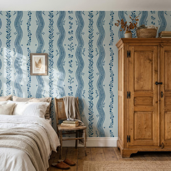 Elsie Delft Revival blue floral stripe wallpaper in a farmhouse bedroom with a wooden armoire, 52 inch repeat