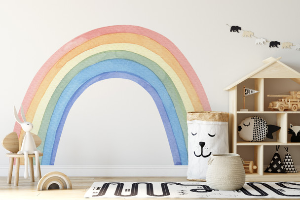 Large pastel watercolor rainbow wall decal displayed in a bright playroom with children’s furniture and toys