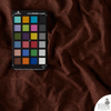 Saddle Brown Waxed Canvas Fabric with color card placed on top for shade accuracy — 10 oz waterproof cotton canvas showing rich brown tone and natural wax finish