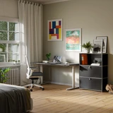Cubox Büroregal mit 3 Ebenen und 2 Klappen in Schwarz mit Ordnern und Pflanze im hellen Homeoffice neben Schreibtisch und Bürostuhl