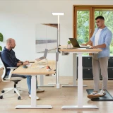 Flexibles Büro mit ofinto Elevate Tischen - zwei Arbeitsplätze in Sitz- und Stehposition getrennt durch Akustik-Trennwand mit Stehmatte