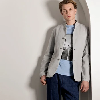 Man wearing a grey stand collar jacket over a graphic tee.