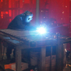 Man wearing protective mask welding a bed frame