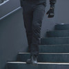 Man walking down stairs wearing the black Rothco Men's Patrol Pants 