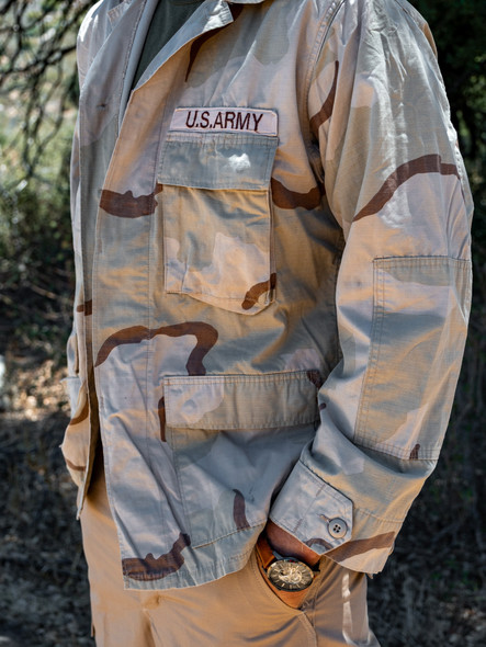 Man standing in grass showing the left arm sleeve with hand in pocket wearing the U.S. Issue 3 Color Desert BDU Shirt, Used Man standing in grass showing the left arm sleeve with hand in pocket wearing the U.S. Issue 3 Color Desert BDU Shirt, Used