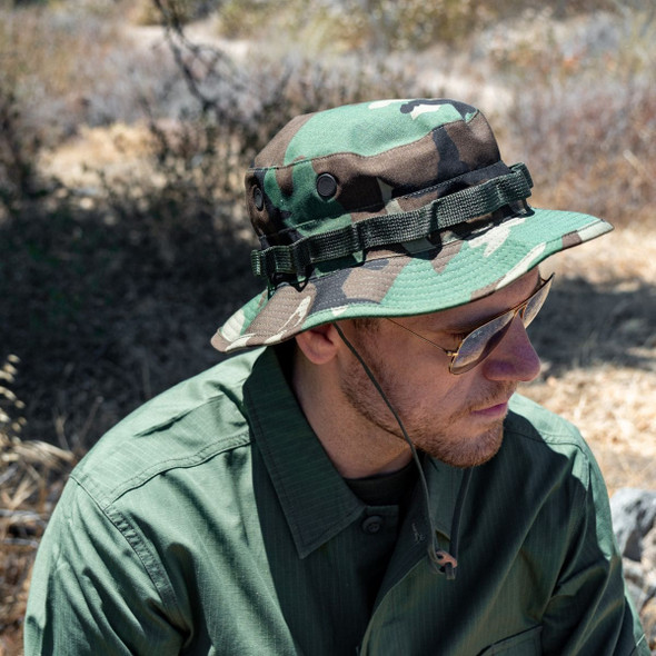 A man with glasses wearing the U.S. Issue Boonie Jungle Hat, NyCo Rip-Stop in the pattern woodland A man with glasses wearing the U.S. Issue Boonie Jungle Hat, NyCo Rip-Stop in the pattern woodland