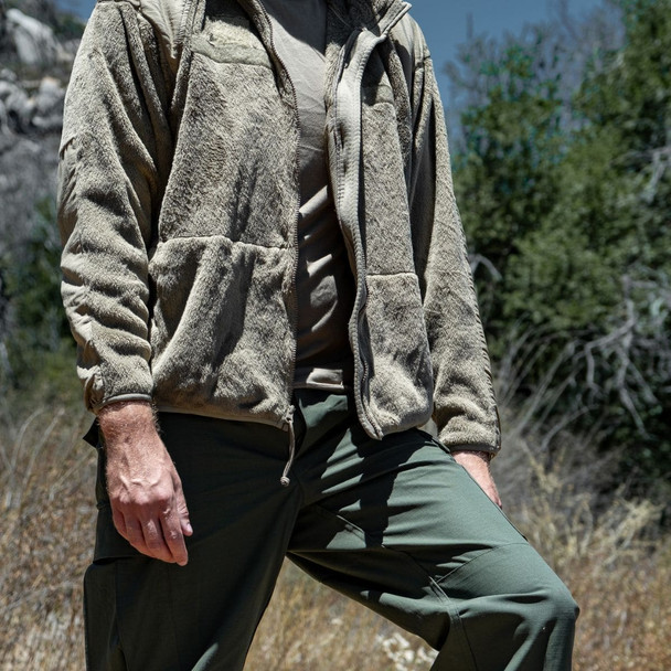 Man in the woods having his left leg propped up wearing the fleece jacket