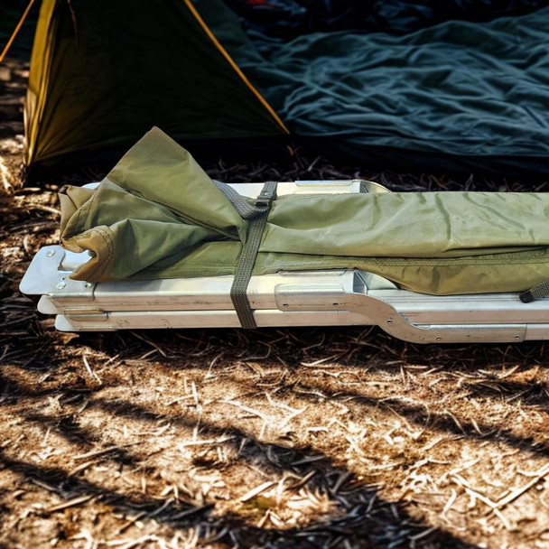 folded army cot in front of a tent on the ground