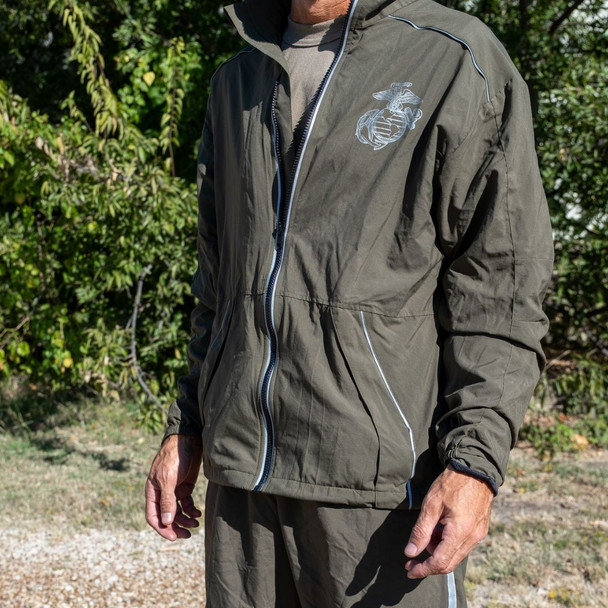 Man outside in front of trees behind him with his hands to the side wearing the USMC Official Physical Training Running Jacket